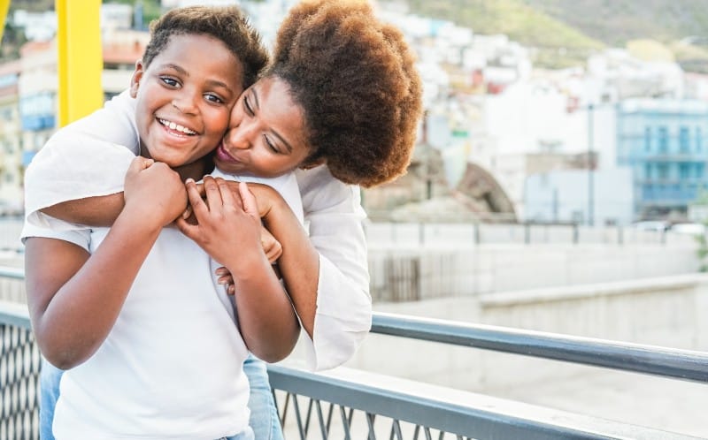 a mother hugging her school aged boy as he smiles