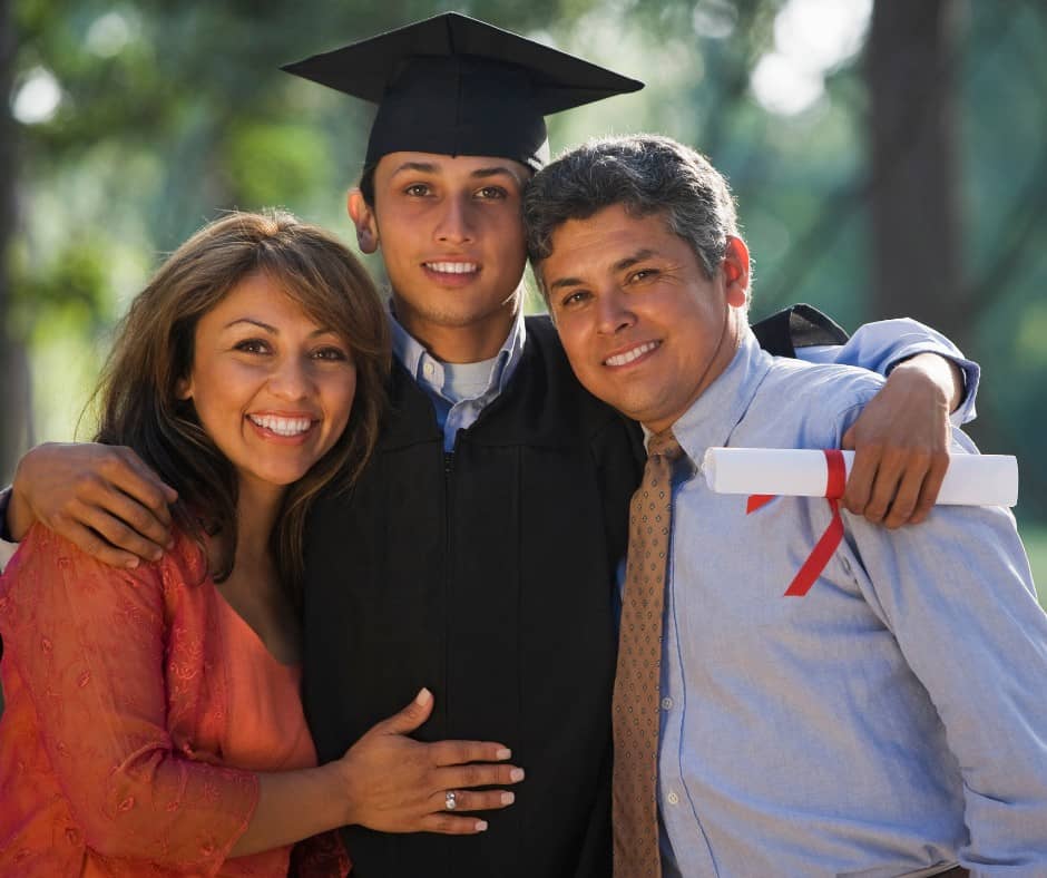 Image of a male student in a black graduation cap and gown with his parents on his left and right side