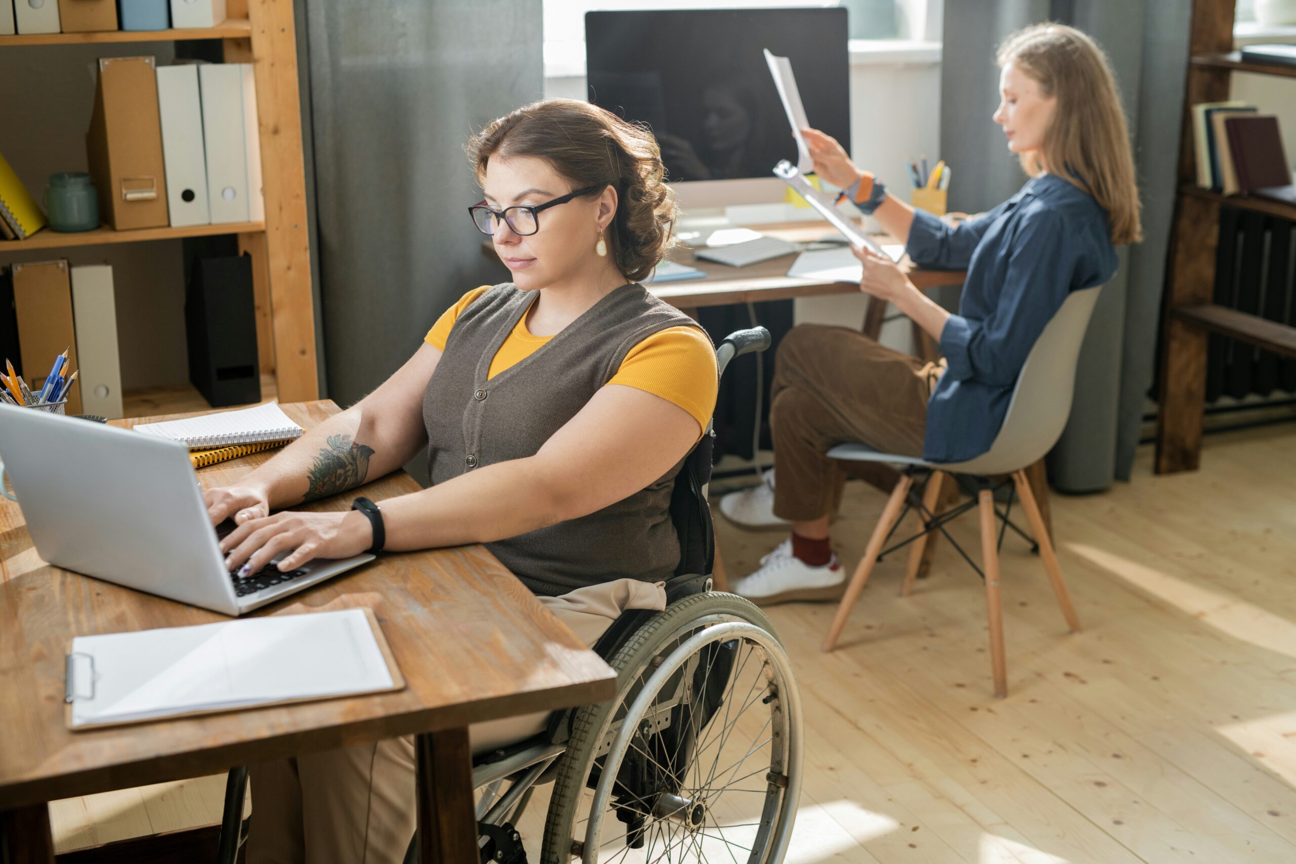 Young woman working at a desk seated in a wheelchair
